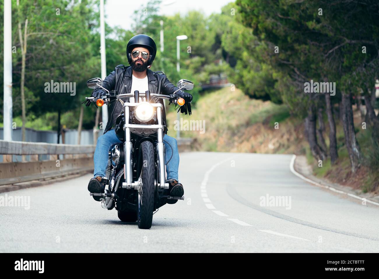 biker con casco, occhiali da sole e giacca in pelle che guida la sua moto in viaggio, concetto di libertà e stile di vita ribelle Foto Stock