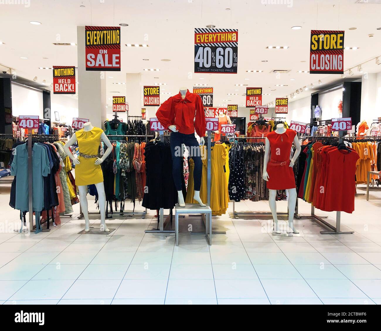 Un centro commerciale del negozio ha vari abiti di moda delle Signore e vestiti in vendita con i segni di chiusura del negozio per un concetto pandemico circa le imprese fallite. Foto Stock