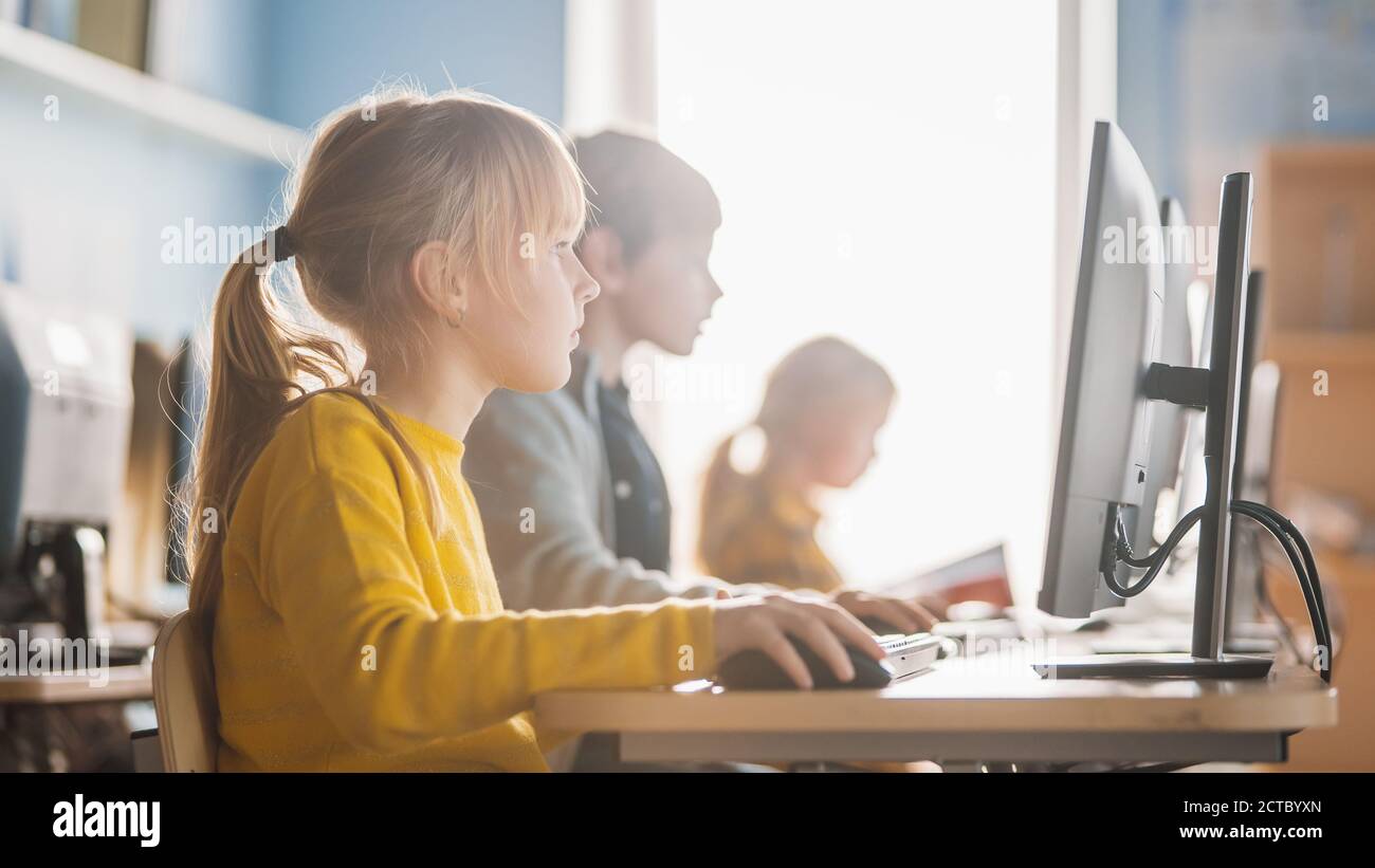 Scuola elementare computer Science Classroom: Ritratto di una smart cute Girl utilizza Personal computer, Informatica didattica, sicurezza Internet, programmazione Foto Stock