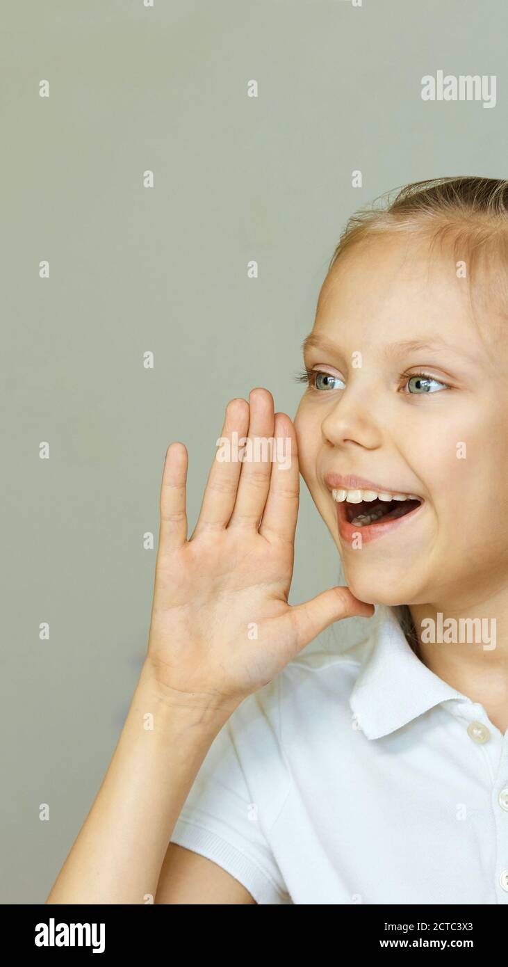 Ritratto sorriso donna piccola. Urlare lateralmente con la mano vicino alla testa. Studio femminile per bambini Foto Stock