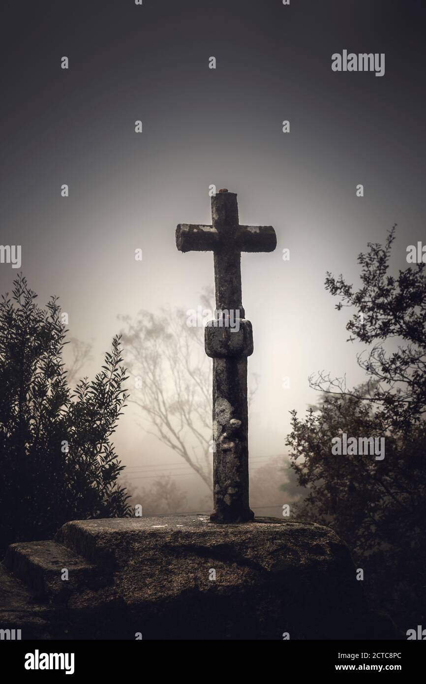 Scatto di una bella croce di pietra religiosa su una nebbia giorno Foto Stock