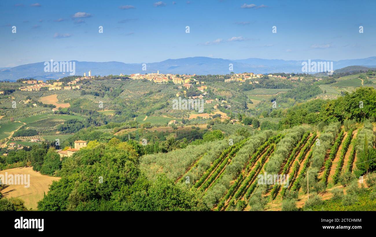 Vista panoramica su colline e vigneti e un villaggio in Toscana, Italia Foto Stock