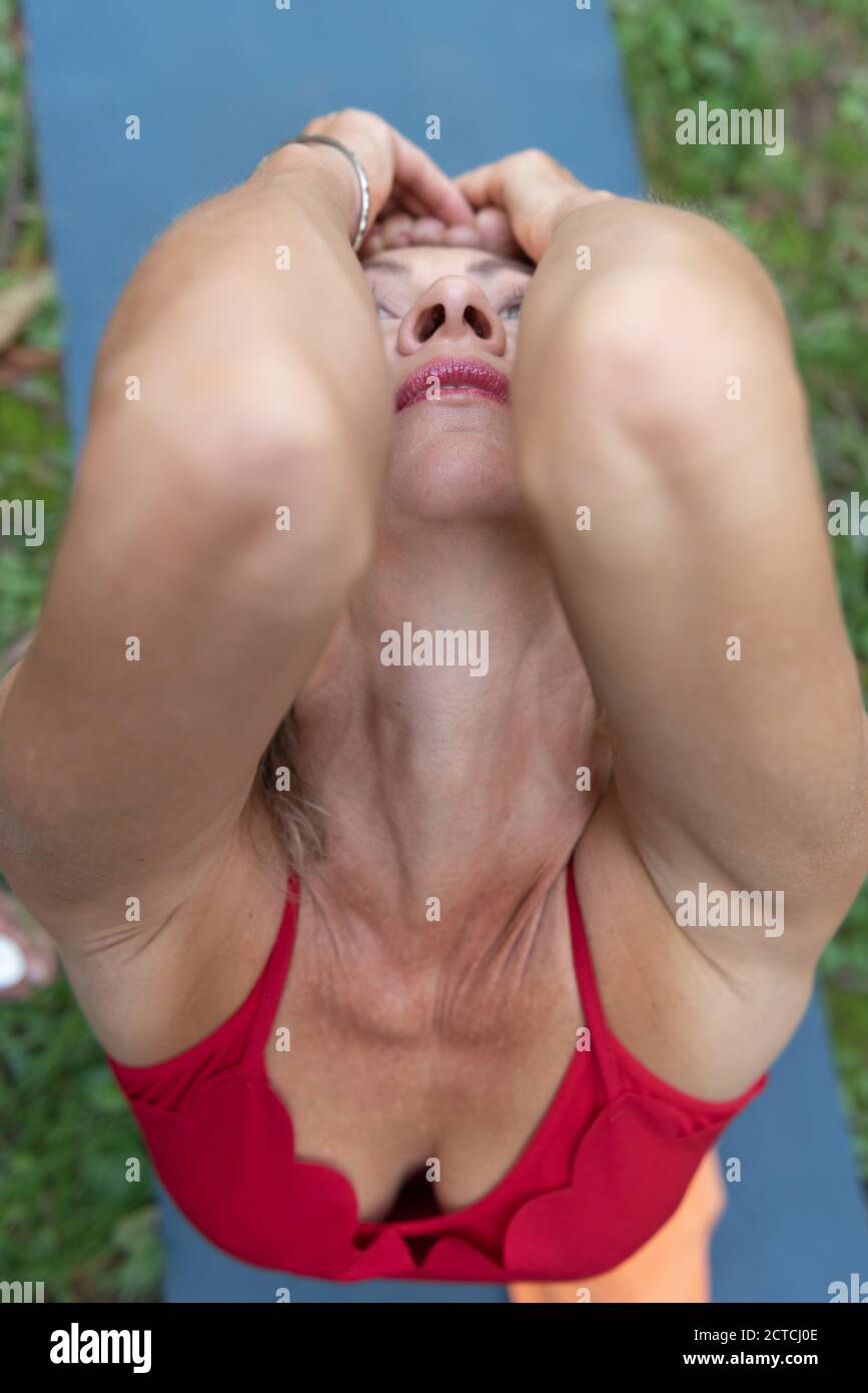 Donna atletica che pratica yoga in natura. Parte delle braccia in primo piano. Esegue una posa di piccione e allunga ulteriormente i tuoi quads. Foto Stock