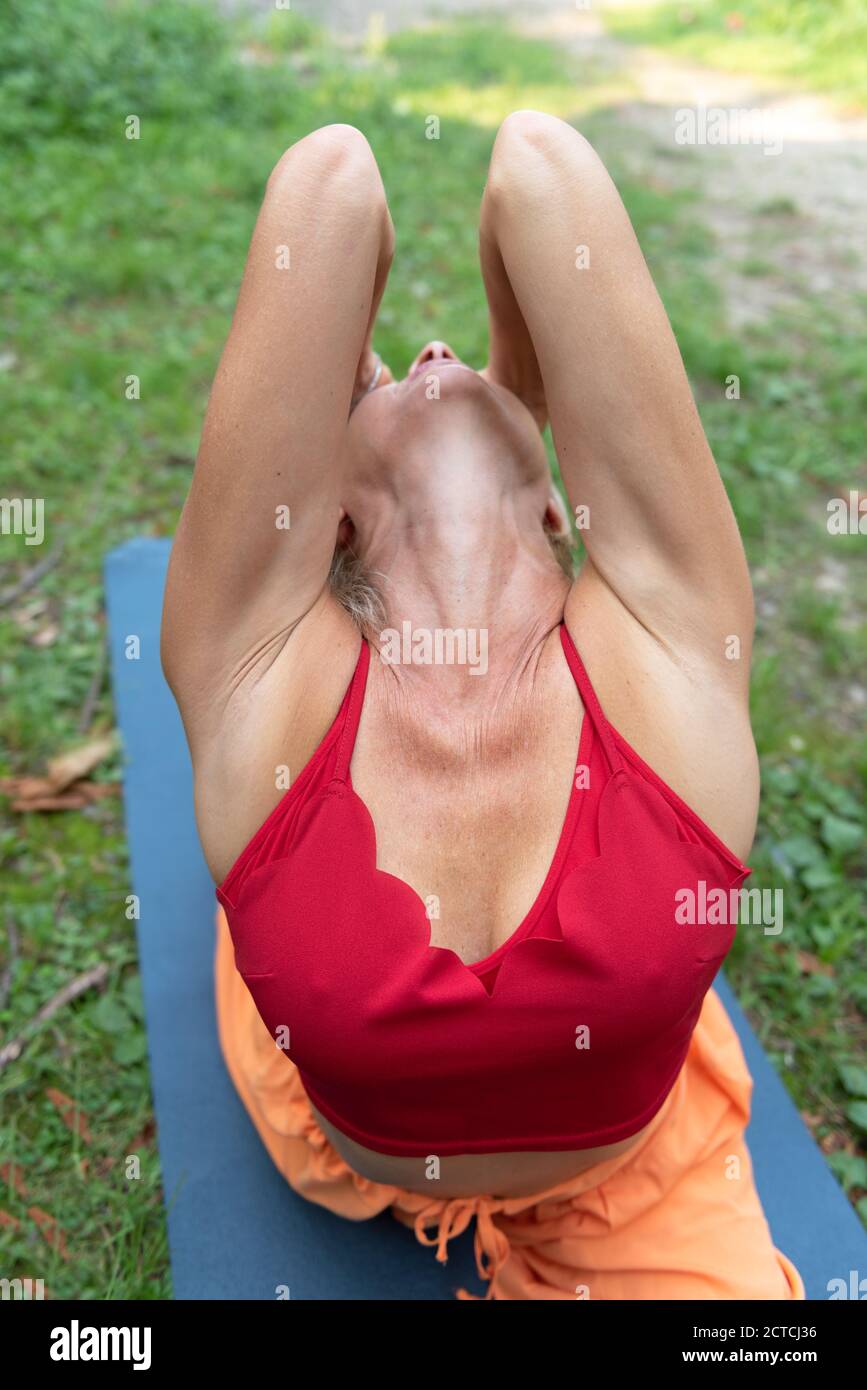 Donna atletica che pratica yoga in natura. Parte delle braccia in primo piano. Esegue una posa di piccione e allunga ulteriormente i tuoi quads. Foto Stock