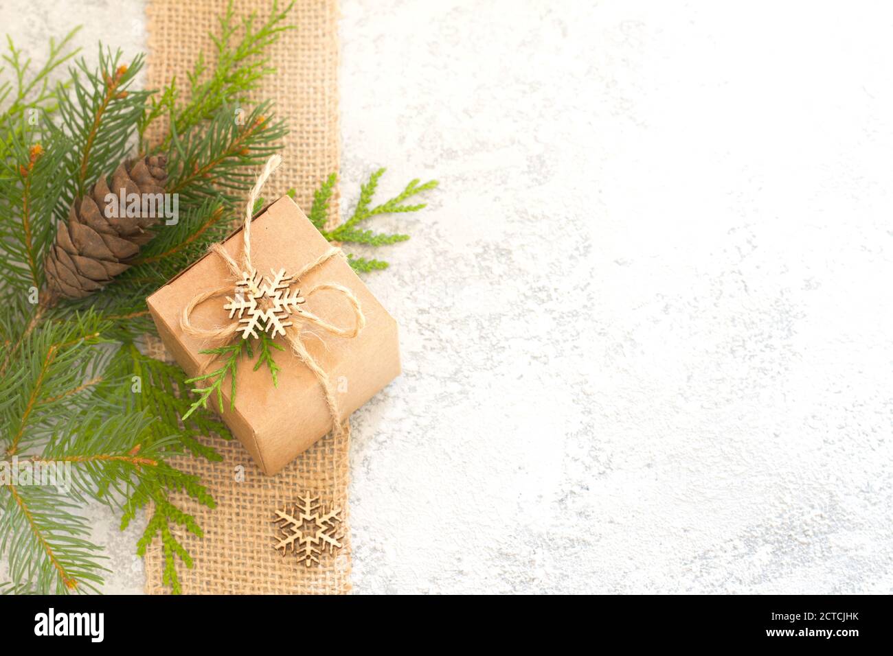 Composizione di Natale. Regalo di Natale, iuta, cono di pino e ramoscelli di abete su sfondo chiaro Foto Stock