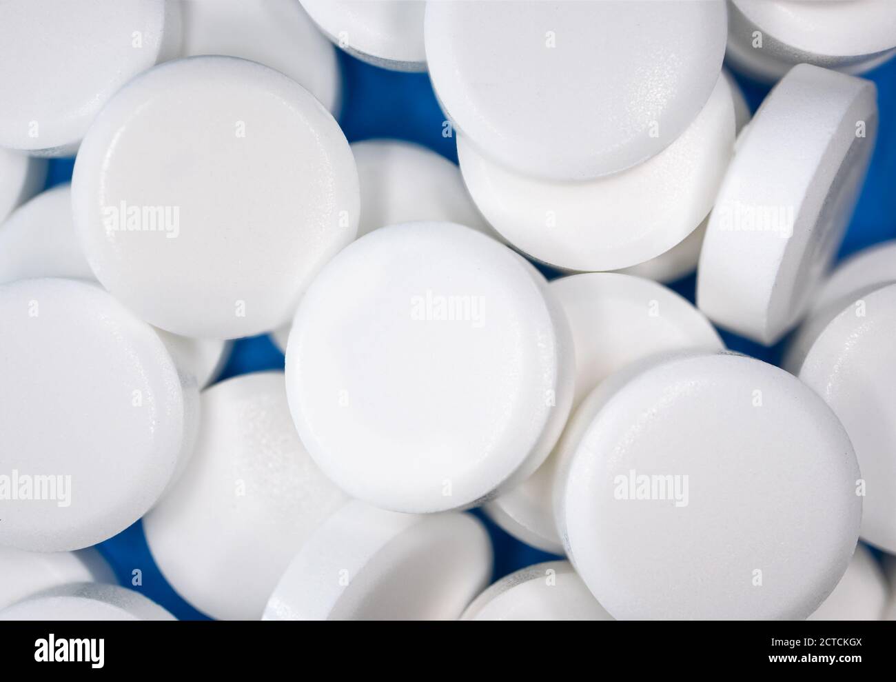 Primo piano di pillole multiple. Molte compresse bianche con sfondo blu. A forma di disco, senza impronte. Farmaco o supplemento. Foto Stock