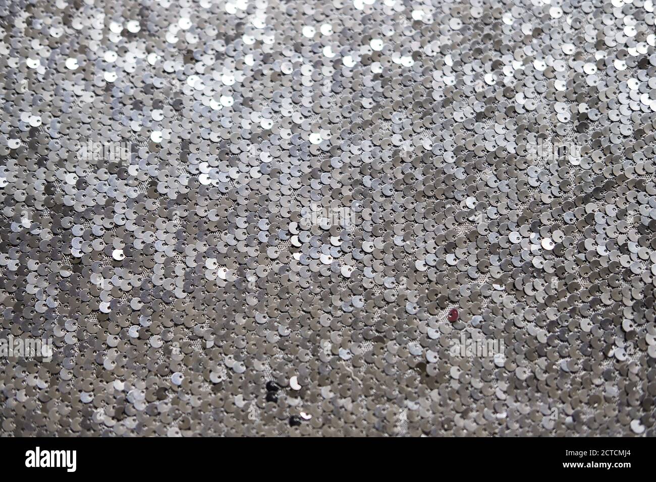 Tessuto a paillettes. Brillante sfondo argento brillante. Capo di abbigliamento con glitter metallizzato per una festa glamour, una festa. Primo piano Foto Stock