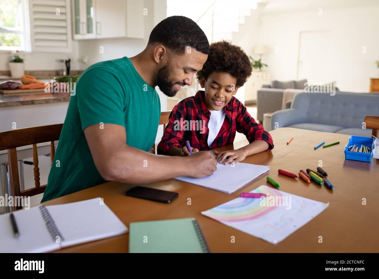 Padre che aiuta il figlio con la pittura a casa Foto Stock