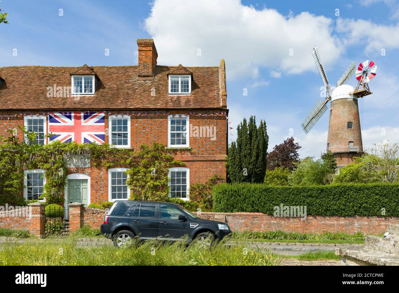 QUAINTON, Regno Unito - 15 maggio 2020. Scena villaggio britannico nel Buckinghamshire, con villaggio verde, bandiera britannica su una casa e mulino a vento in funzione Foto Stock