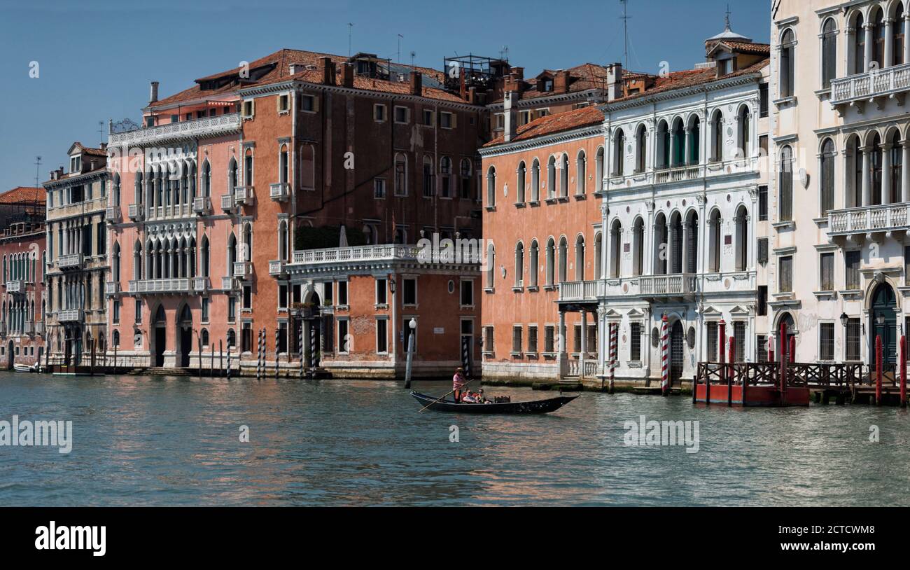 Un uomo che guida una gondola su un canale con residenze veneziane sullo sfondo, Venezia, Italia. Foto Stock