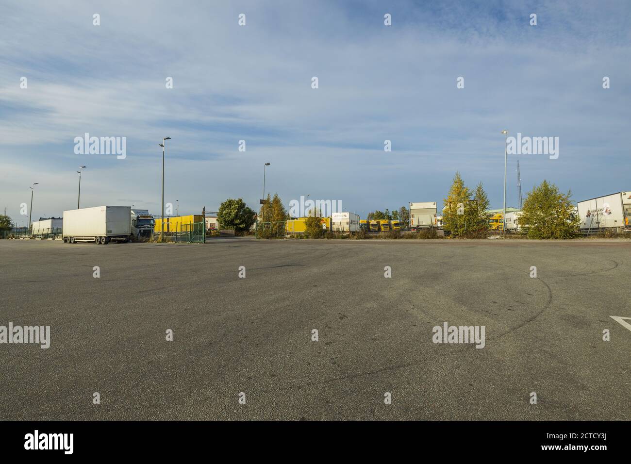 Splendida vista panoramica del terminal logistico DHL. Camion parcheggiati su un territorio enorme su cielo blu con sfondo nuvole bianche. Foto Stock