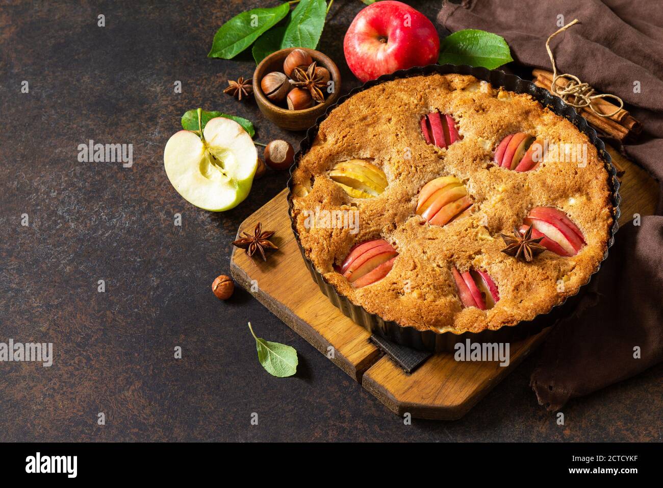 Cottura stagionale di mele. Torta di mele con nocciole e cannella su un rustico tavolo di legno. Spazio libero per il testo. Foto Stock