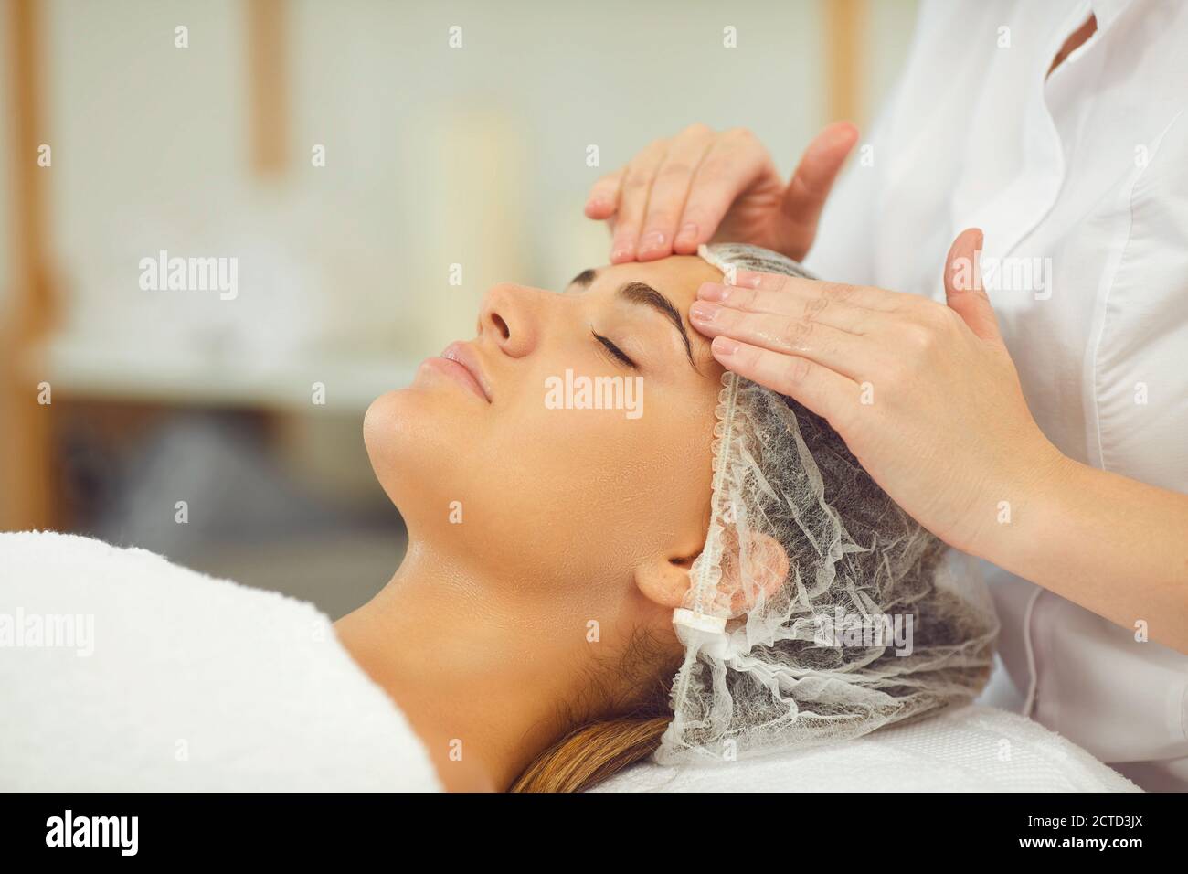Donna che ottiene procedura di massaggio viso rilassante trattamento da cosmetologist Foto Stock