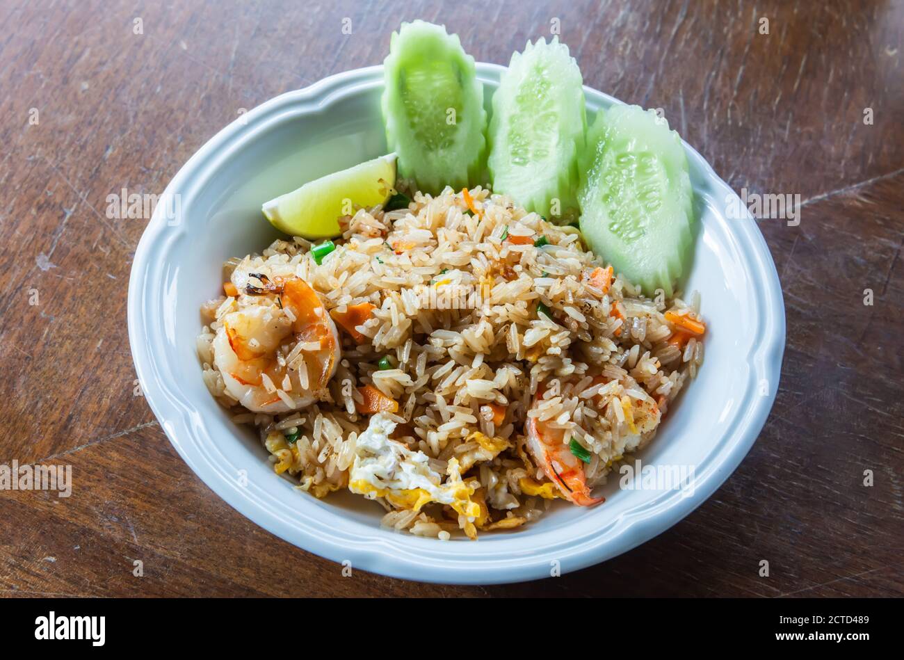 Riso fritto in stile thailandese con uova e gamberi, servito con limone e cetriolo. Foto Stock