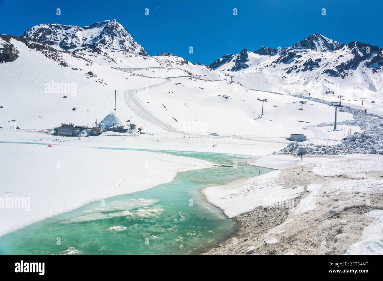 Paesaggio montuoso innevato intorno alla stazione di montagna di Eisgrat, nel ghiacciaio Stubai in Tirolo, Austria, con ruscello ghiacciato. Foto Stock