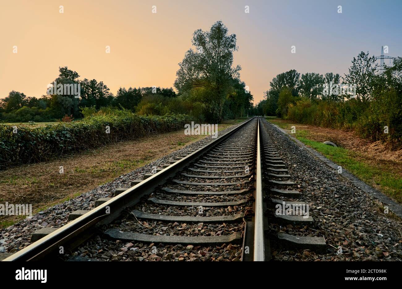 Ferrovia attraverso la natura di campagna al tramonto in una bella estate sera Foto Stock