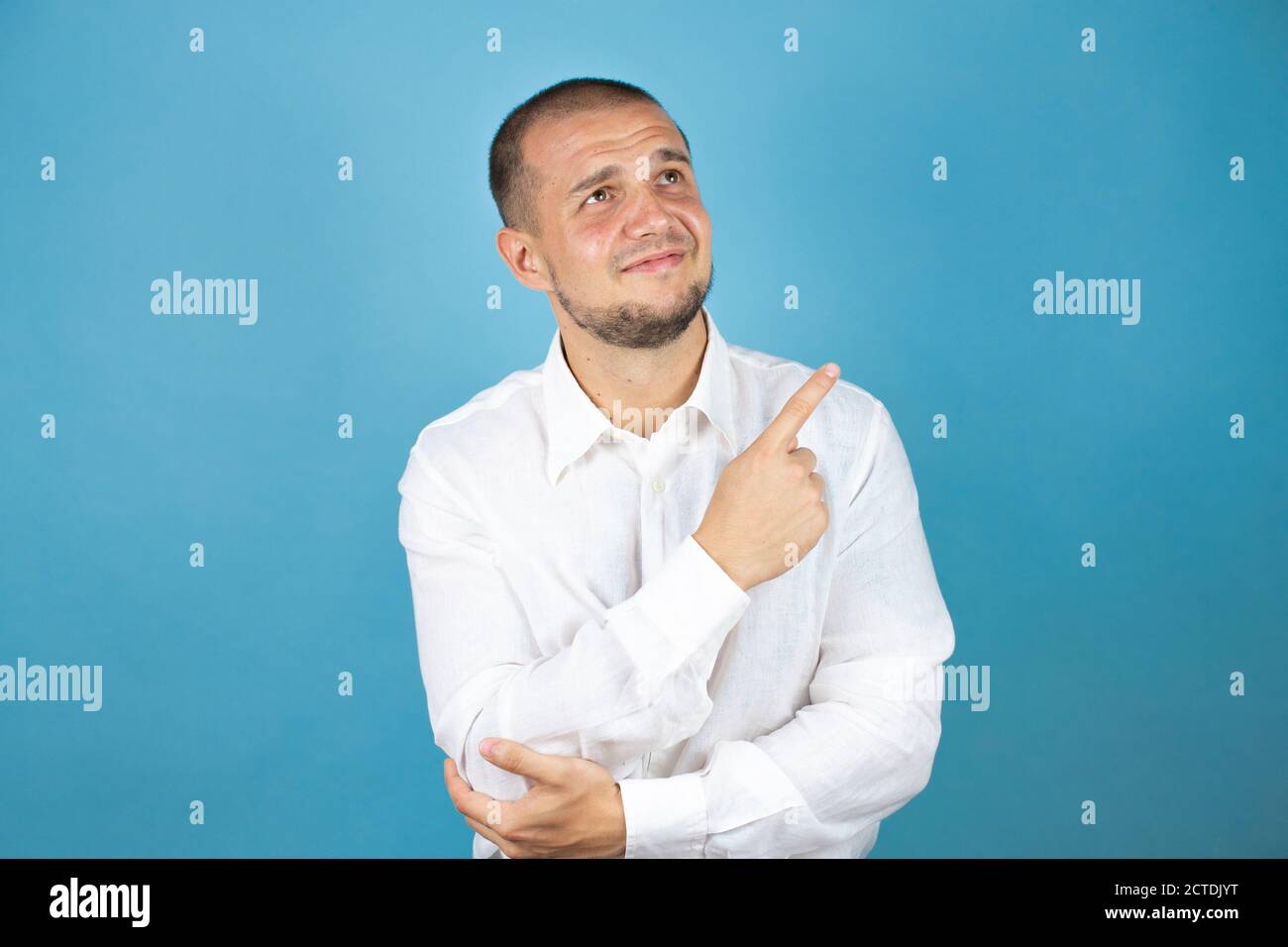 Uomo d'affari russo che indossa una camicia bianca su sfondo blu che punta il dito verso l'alto. Foto Stock