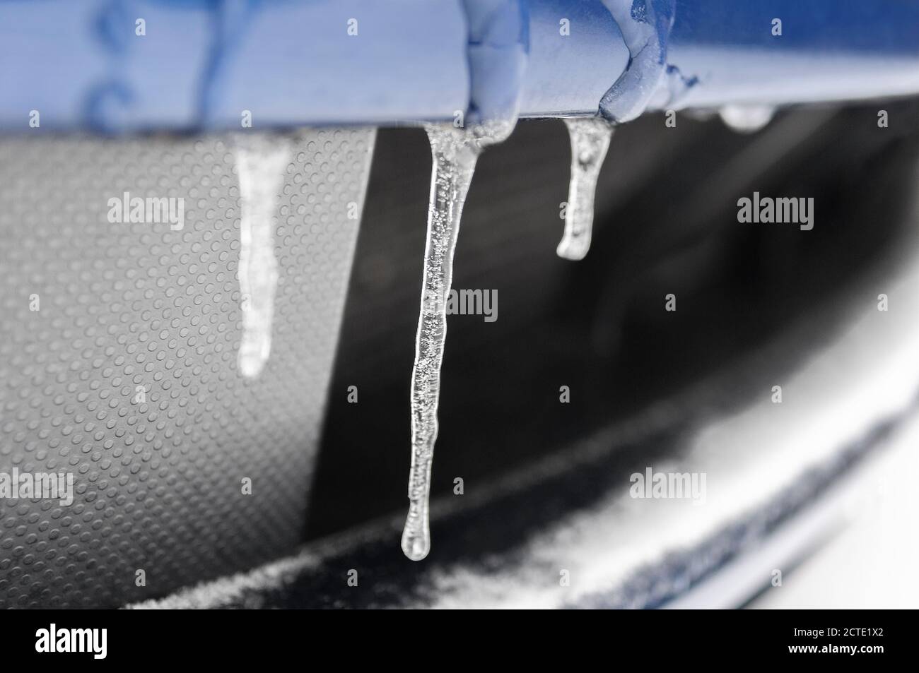 Piccoli icicles che si formano sulla parte inferiore anteriore di un'automobile Foto Stock