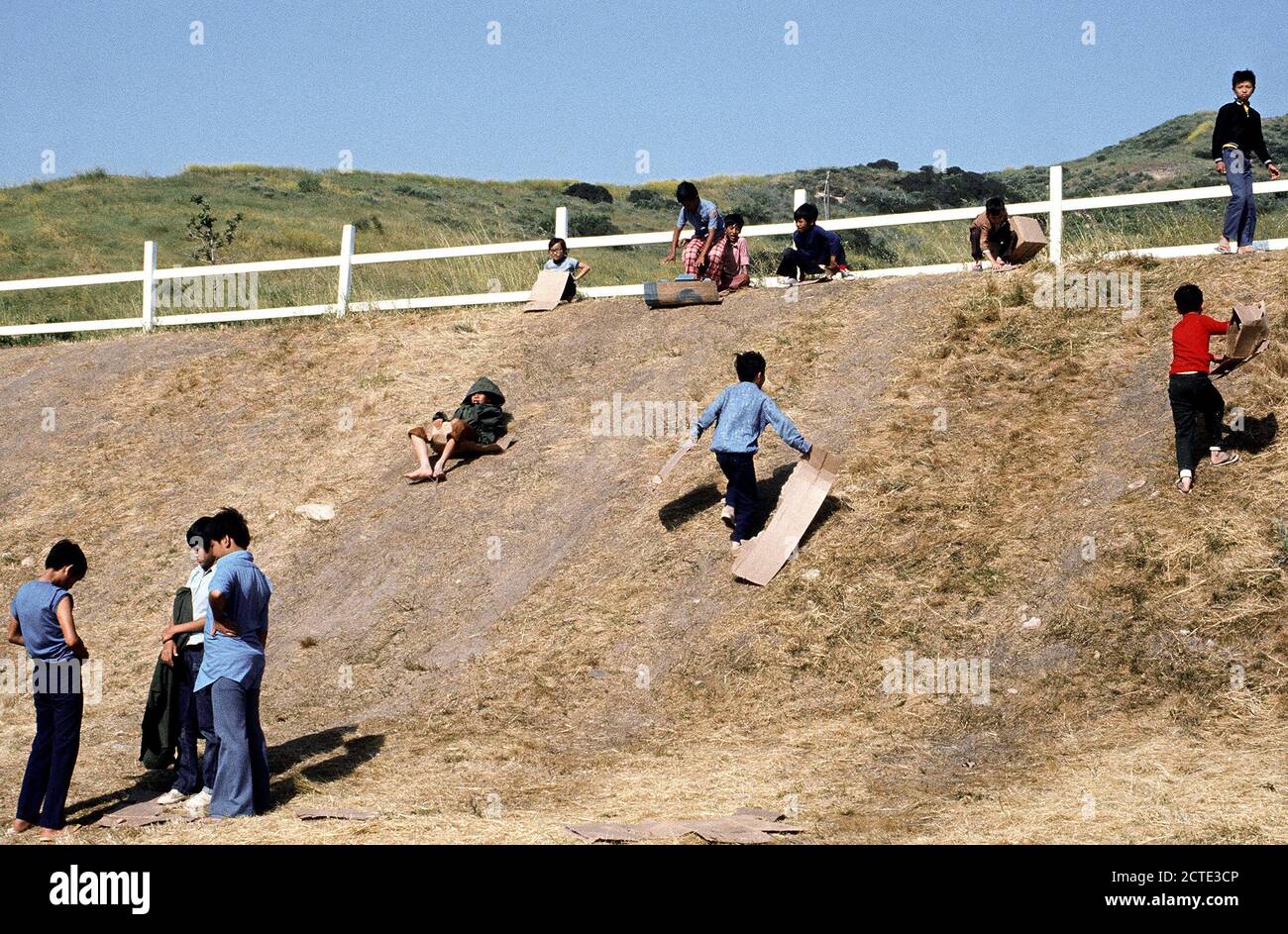 1975 - Bambini scorrere su una collina a una temporanea struttura alloggiativa per rifugiati vietnamiti. Foto Stock