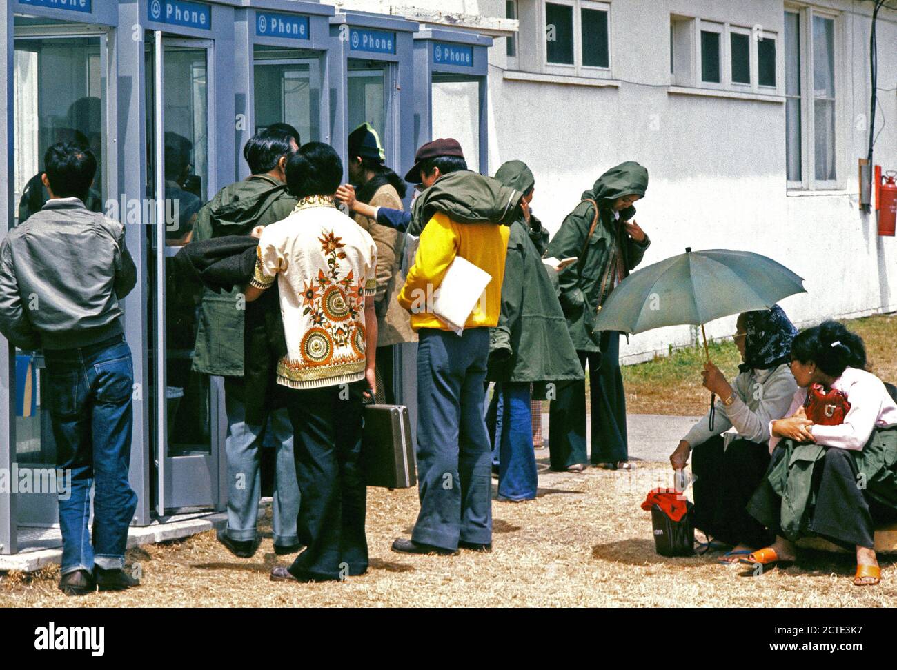 1975 - rifugiati vietnamiti attendere prima di utilizzare i telefoni a una temporanea struttura di alloggiamento. Foto Stock