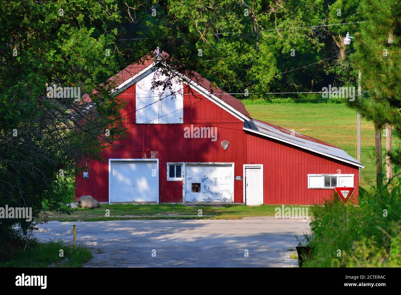 Mt. Carroll, Illinois, Stati Uniti. Un vecchio fienile di legno rosso si trova ai piedi di una strada inclinata a pochi isolati dal centro della città in una piccola città. Foto Stock