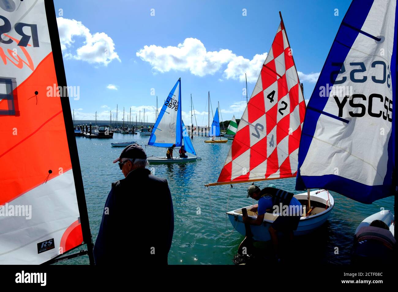 I gommoni a vela con vele colorate si riuniscono intorno allo scivolo Sull'estuario dello Yar al Yarmouth Sailing Club sull'isola Di Wight Foto Stock