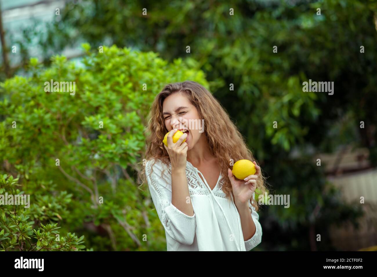 Donna in bianco che tiene due limoni nelle mani Foto Stock