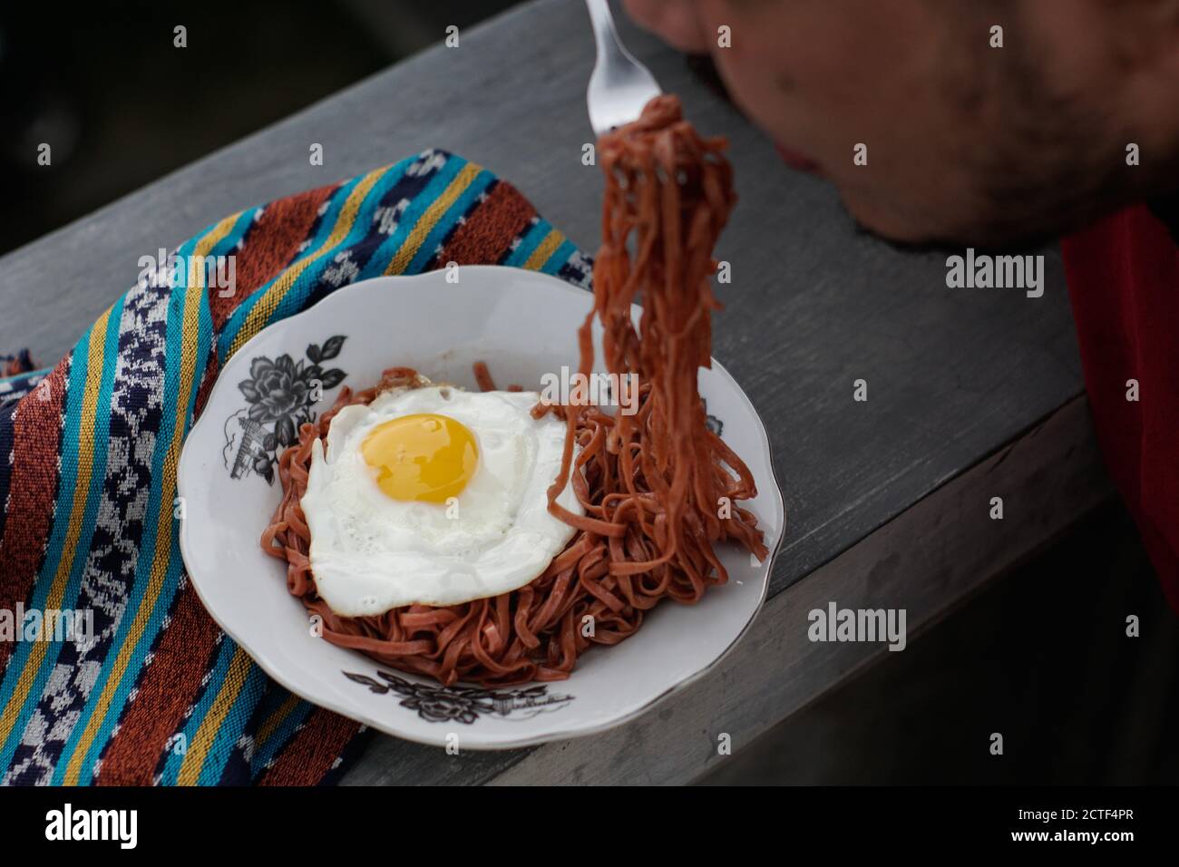 I tagliatelle fritte vengono gustati con uova fritte su un Piatto con un tipico ornamento di stoffa etnica Indonesiana Foto Stock