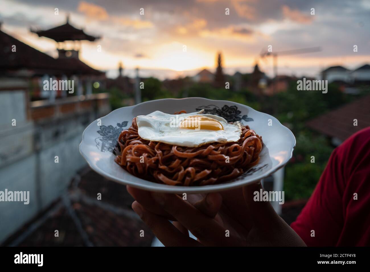 I tagliatelle fritte vengono gustati con uova fritte su un Piatto con un tipico ornamento di stoffa etnica Indonesiana Foto Stock