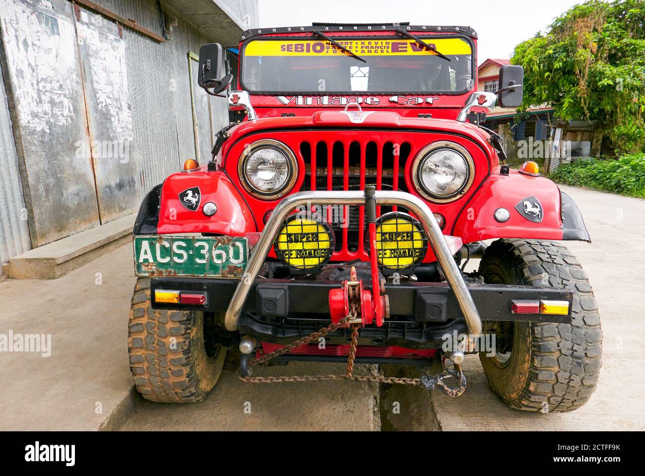 Vista frontale ravvicinata di un'auto fuoristrada a 4 ruote motrici in stile jeep di colore rosso con ruote, paraurti e fari molto grandi, vista a Sagada, Filippine Foto Stock