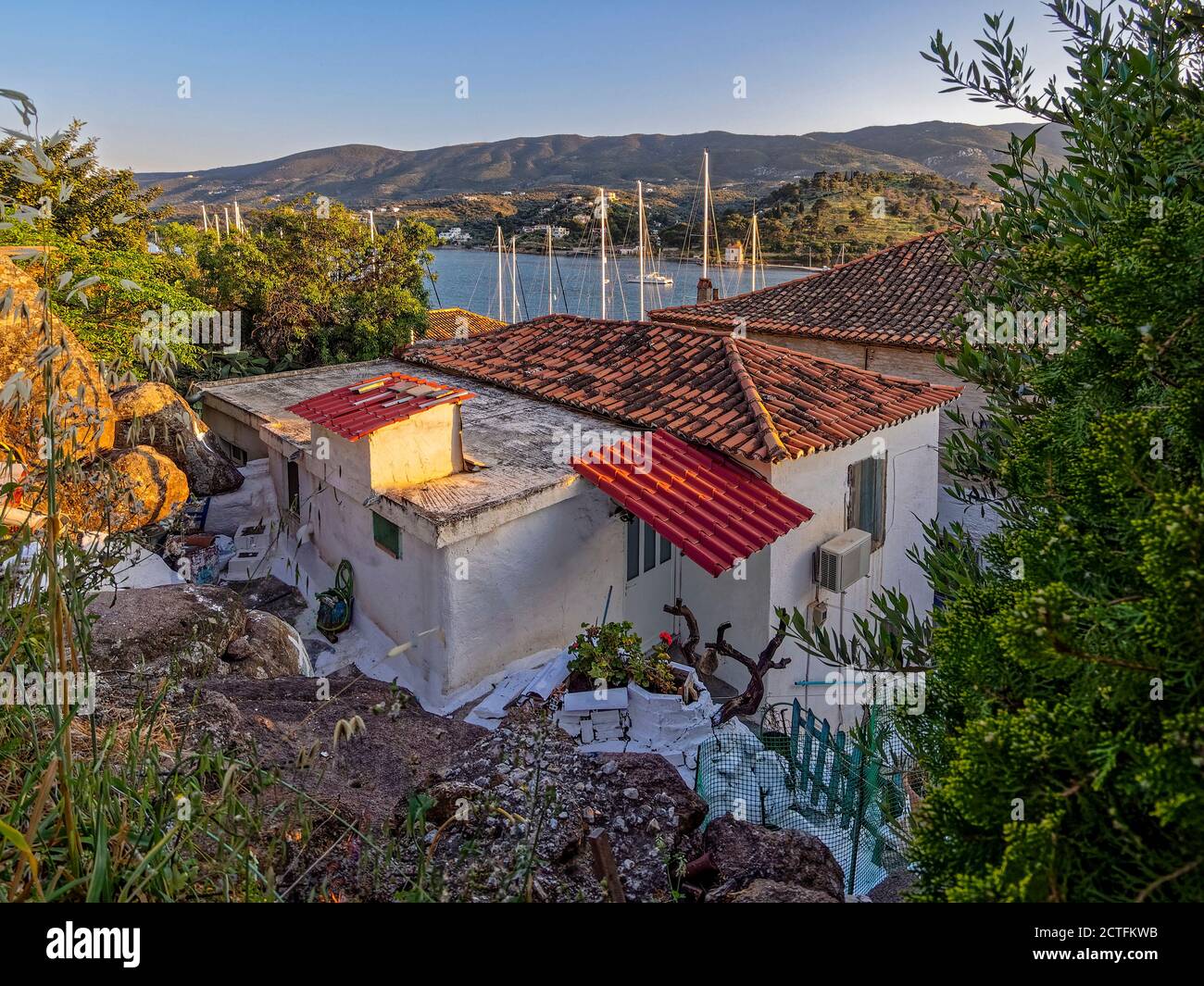 Casa con una vista. I montanti degli yacht e il Il mare blu all'orizzonte testimonia del porto nascosto di Poros dietro le vecchie case arroccate sulle rocce a. Foto Stock