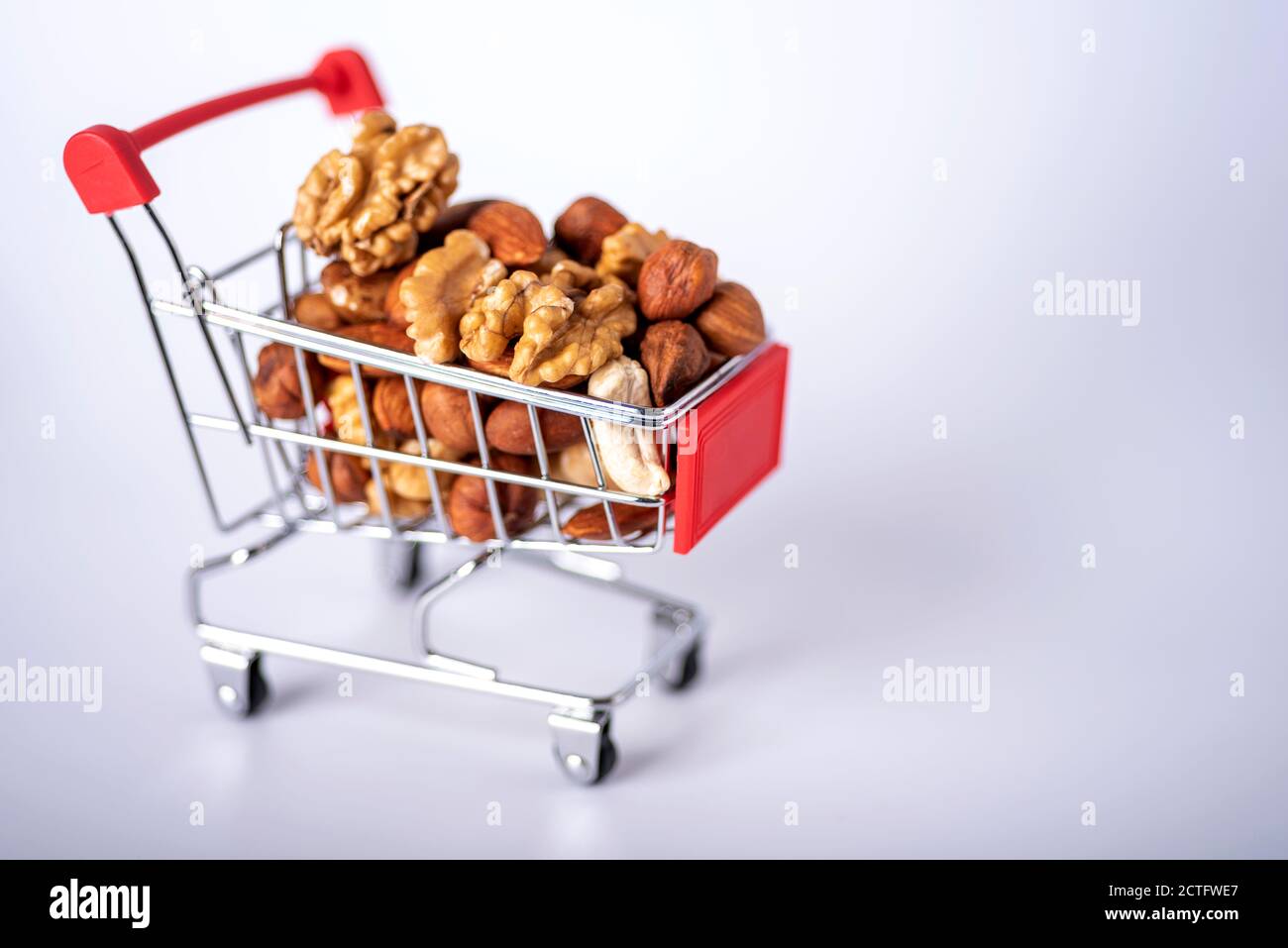 Noci diverse in un carrello su sfondo bianco. Il concetto di cibo sano e sano. Una varietà di dadi. Foto Stock