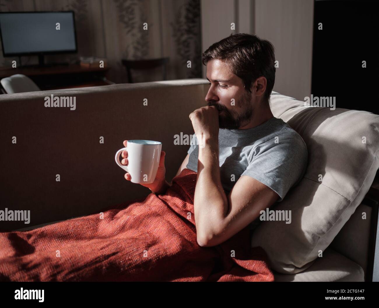 Giovane uomo malato che beve una medicina della farmacia o tè caldo per andare sano a casa. L'idea e il concetto di prendersi cura della vostra salute e malattie Foto Stock