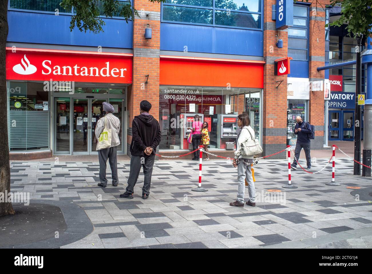 Le persone si accodano pur mantenendo le distanze sociali, al di fuori della Santander Bank di Slough, Berkshire, Regno Unito Foto Stock