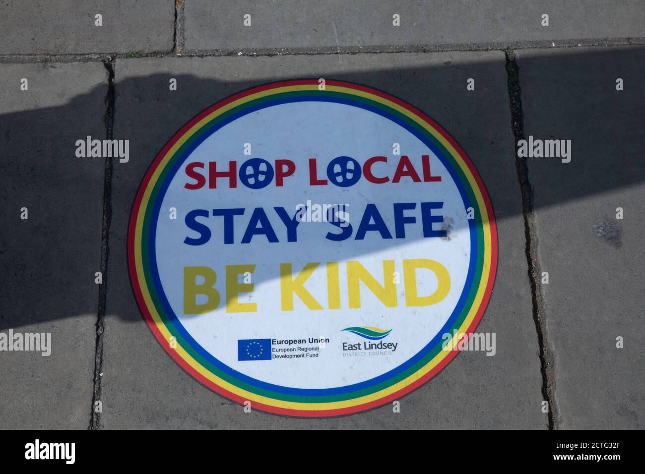Fai shopping nel locale, resta sicuro, fai un cartello con la scritta Be Kind sul marciapiede a Louth, Lincolnshire, in una giornata di sole Foto Stock