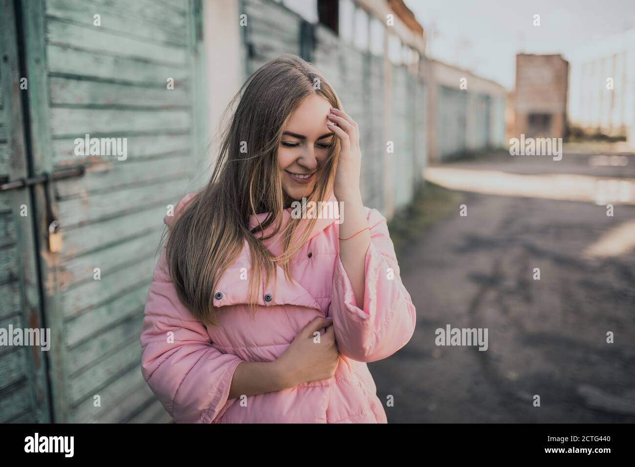 Giovane splendida ragazza bionda vestita giacca rosa moda e blu jeans Foto Stock