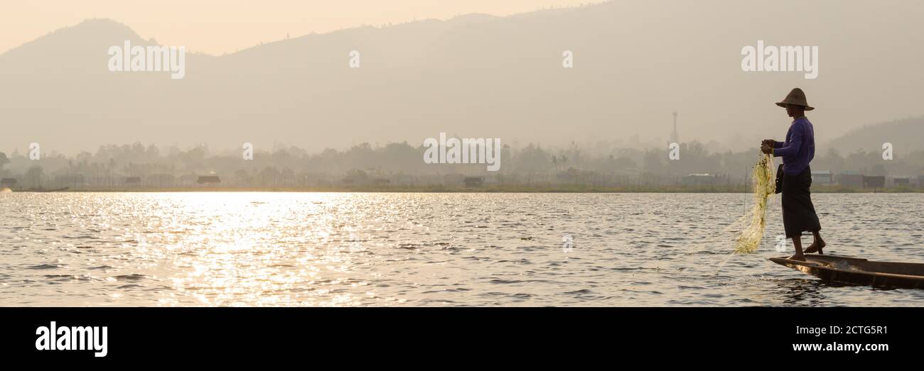 Intha tradizionale gamba canottaggio pescatore sul lago di Inle al tramonto, Birmania, Myanmar Foto Stock