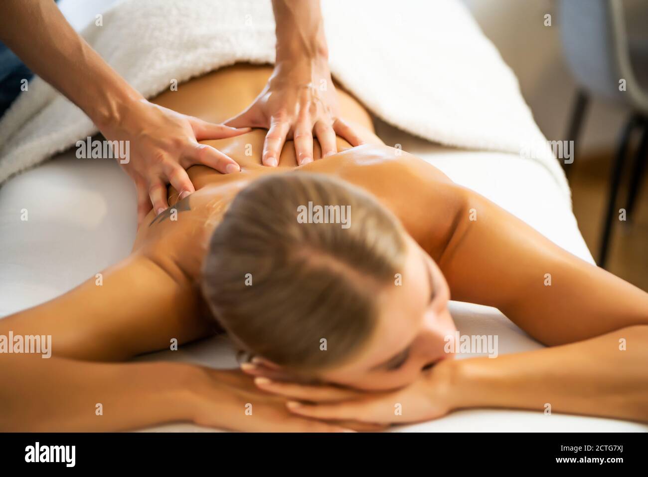 Massaggiatore professionista che fa massaggio terapeutico. Donna che ama il massaggio a casa sua. Giovane donna che ottiene massaggio rilassante del corpo. Foto Stock