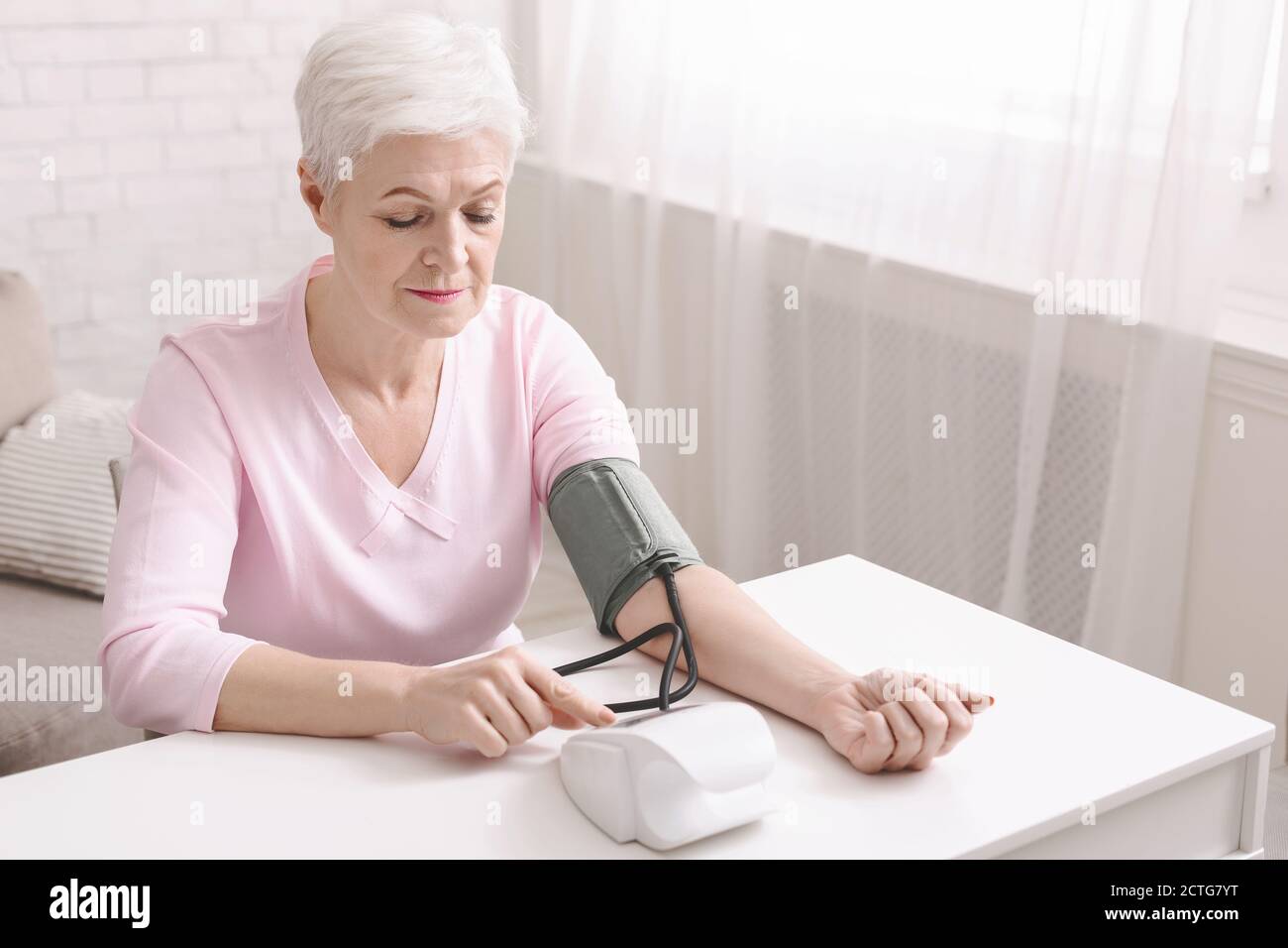Signora anziana con ipertensione che misura la pressione sanguigna lei stessa Foto Stock