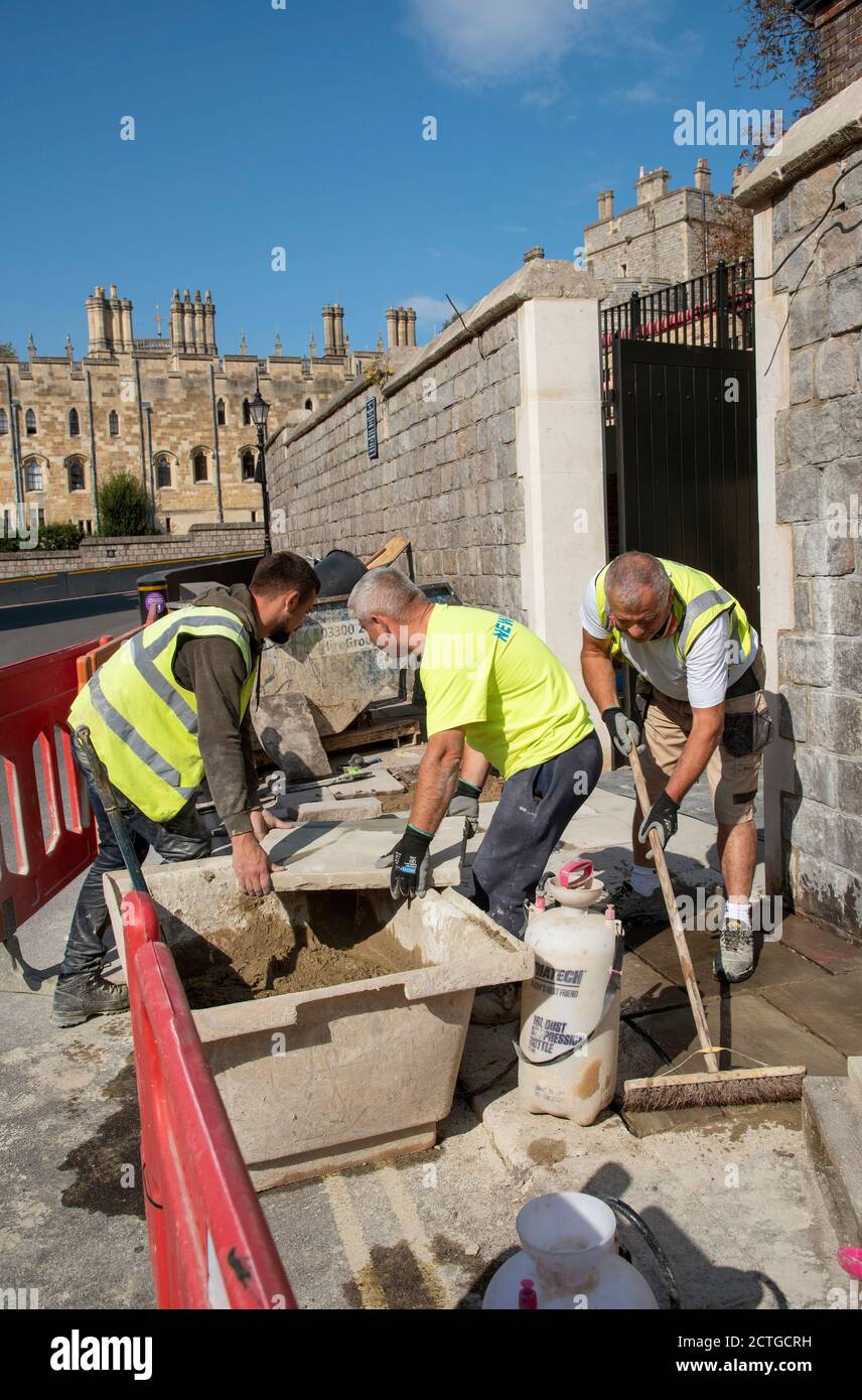 Windsor, Berkshire, Inghilterra, Regno Unito. 2020. Operai che posano lastre di pavimentazione sullo sfondo del Castello di Windsor. Foto Stock
