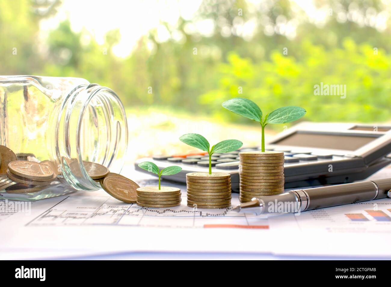 Piantare piccoli alberi verdi su monete e calcolatrici, contabilità finanziaria concetti e risparmiare denaro. Foto Stock