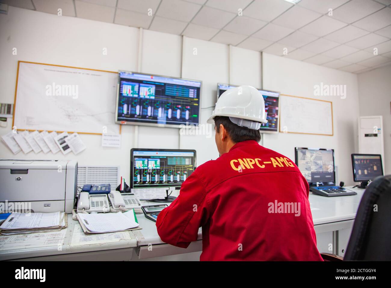 Regione di Aktobe/Kazakhstan - maggio 04 2012: Stabilimento di lavorazione del petrolio. Addetto alla raffineria o ingegnere in abbigliamento da lavoro rosso e lavorazione del controllo del casco bianco. Foto Stock