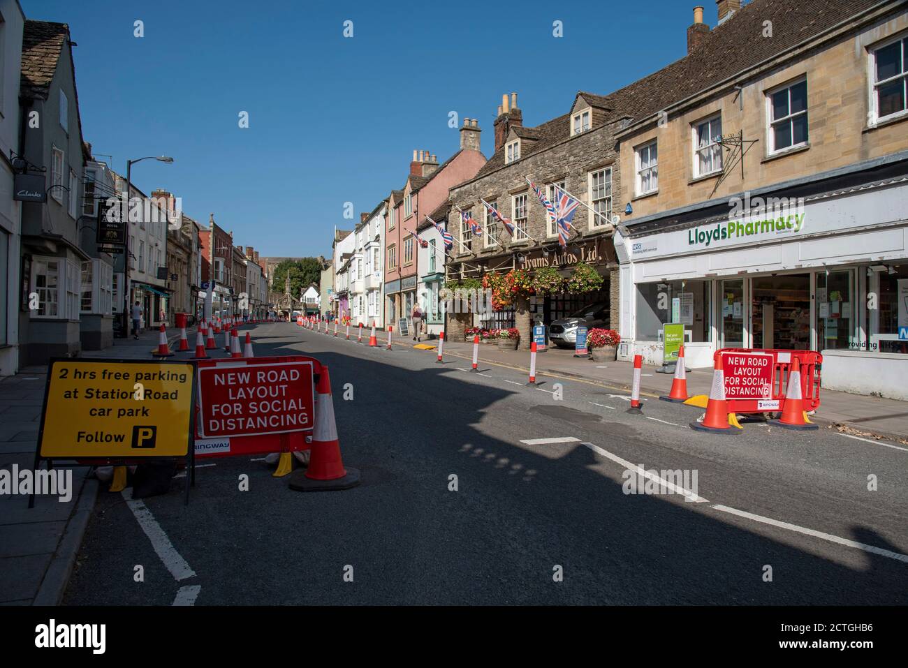 Malmesbury, Wiltshire, Inghilterra, Regno Unito. 2020, coni di traffico di distanza sociale e segnaletica nella strada principale di questa storica città mercato. Ciclista e cic Foto Stock