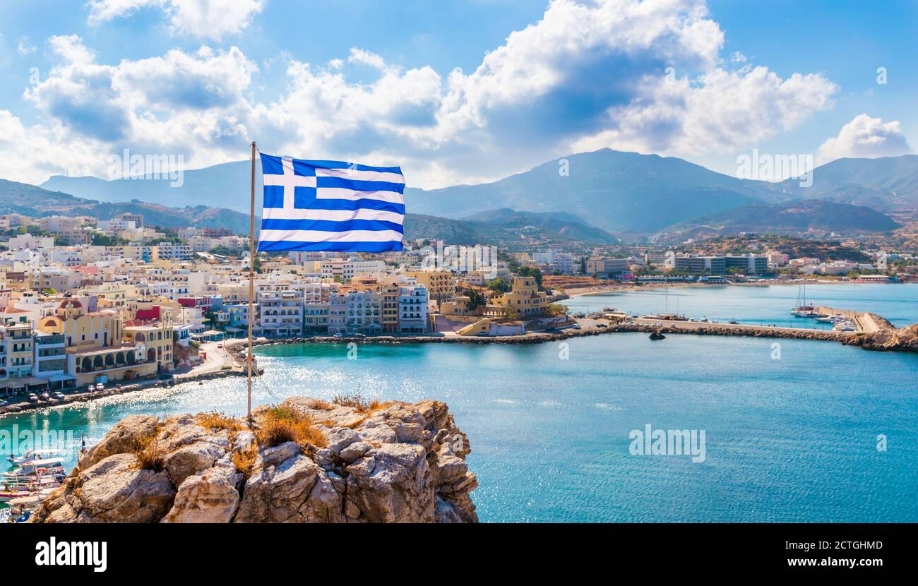 Vista panoramica della baia di Pigadia, città e porto con bandiera greca, isola di Karpathos, Grecia Foto Stock