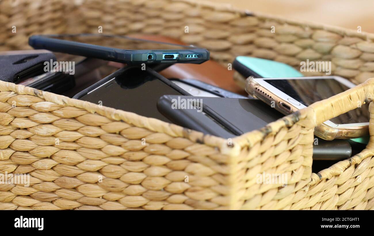 Telefono cellulare gratuito aule e scuole. Un contenitore di archiviazione riempito con più telefoni di studenti o utenti. Cestino di canna riempito con mobile Foto Stock