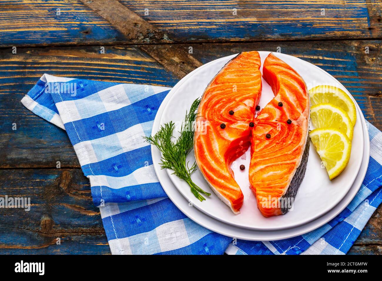 Trota norvegese cruda. Pezzi di pesce fresco, limone, aneto, pepe, sale. Vecchio tavolo in legno Foto Stock