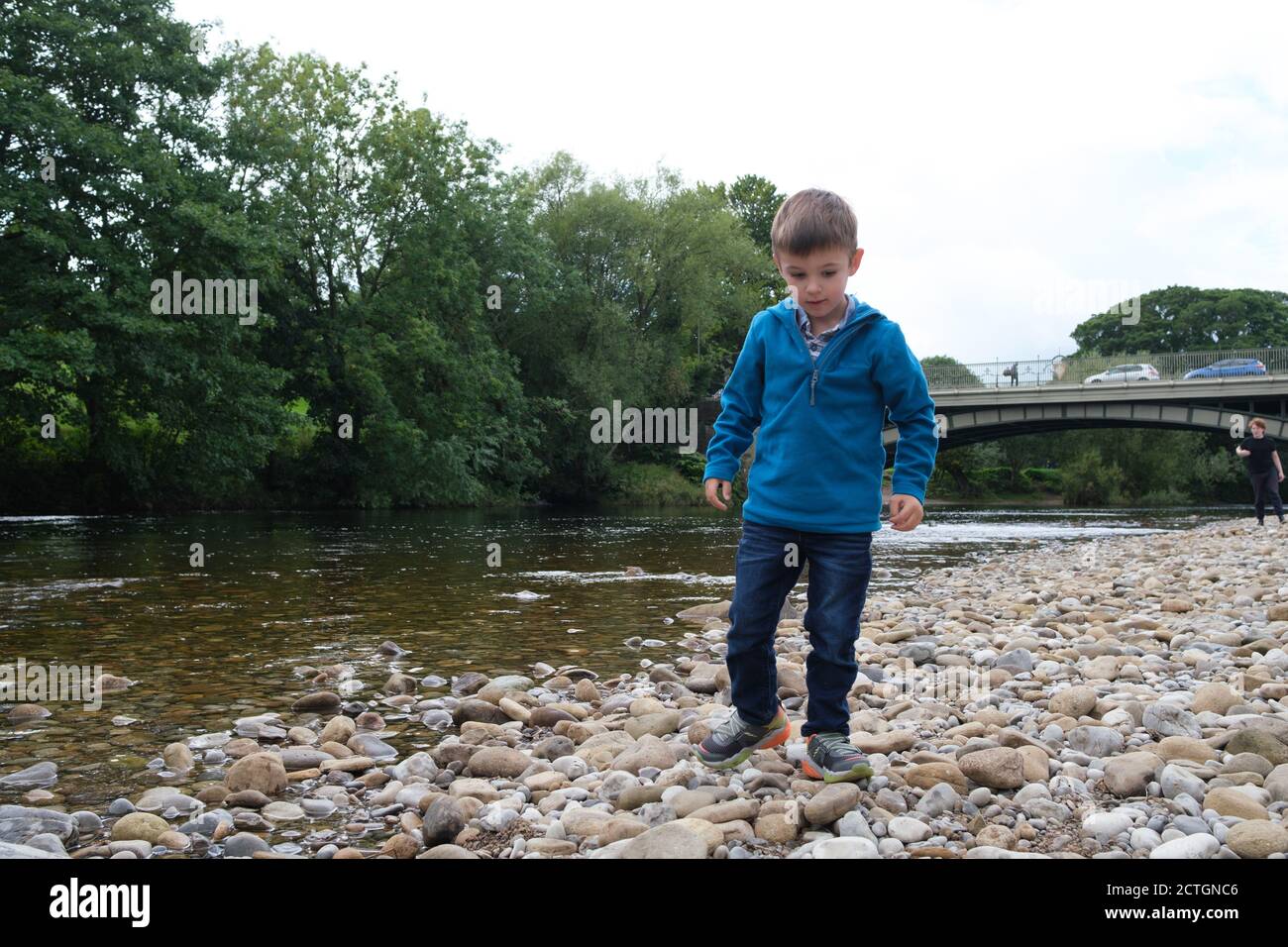 Ragazzo di quattro anni che gioca con pietre sul lato del fiume Wharfe in Ilkley West Yorkshire. Foto Stock