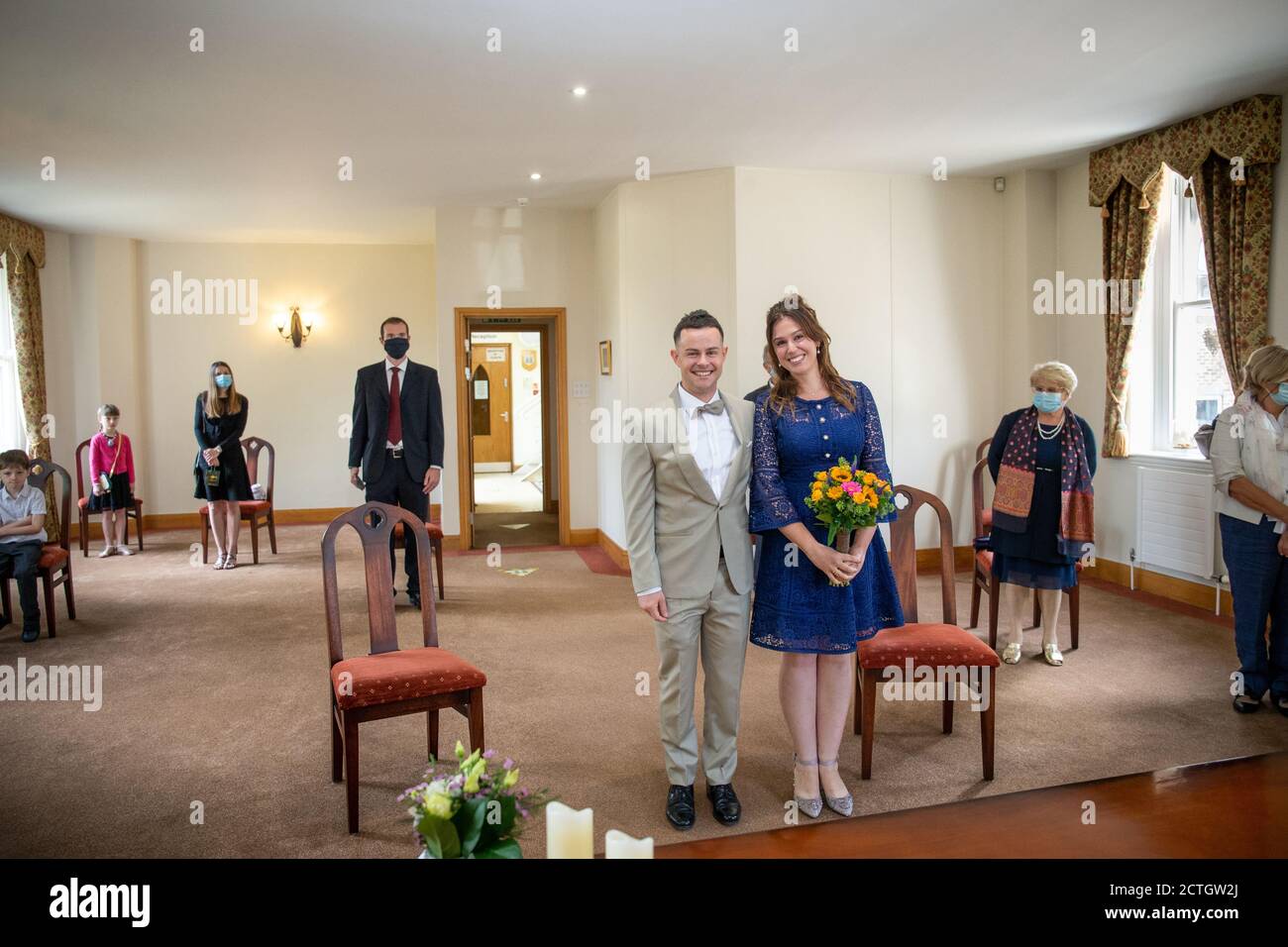 Coppia sposarsi presso l'ufficio del registro di St Albans durante la pandemia di Coronavirus / Covid-19 2020. Con gli ospiti che indossano maschere per il viso e rivestimenti per il viso Foto Stock