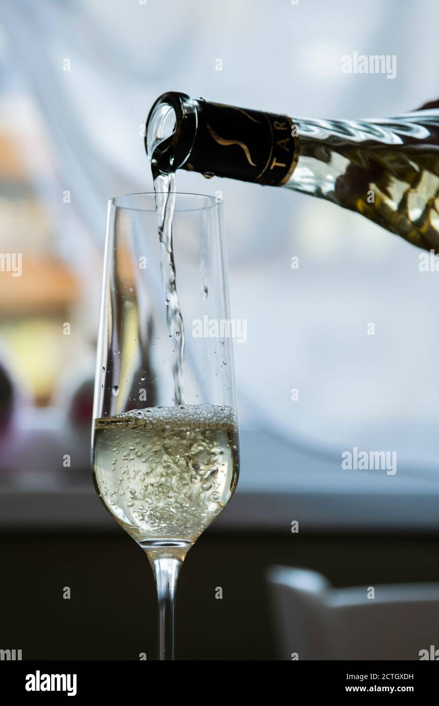 Una bottiglia di vino versa il vino bianco in un vino vetro Foto Stock