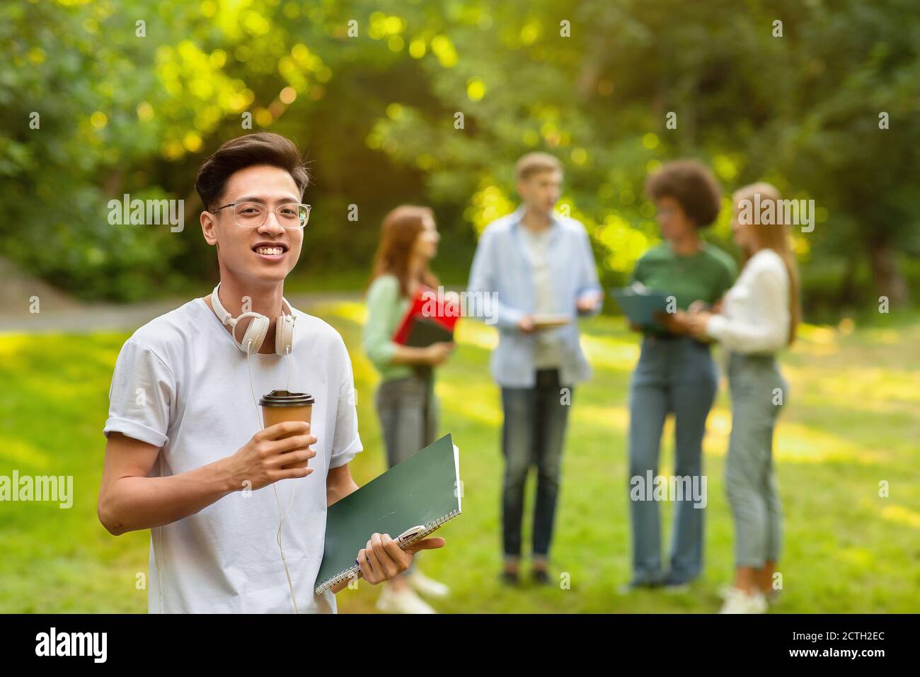 Vita del campus. Asian Student Guy in posa con i notepad e caffè al Campus Foto Stock